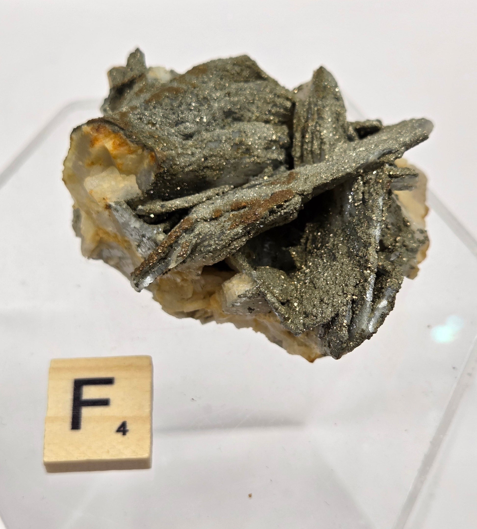 Mineral sample on a white background with a Scrabble tile spelling 'F4'.