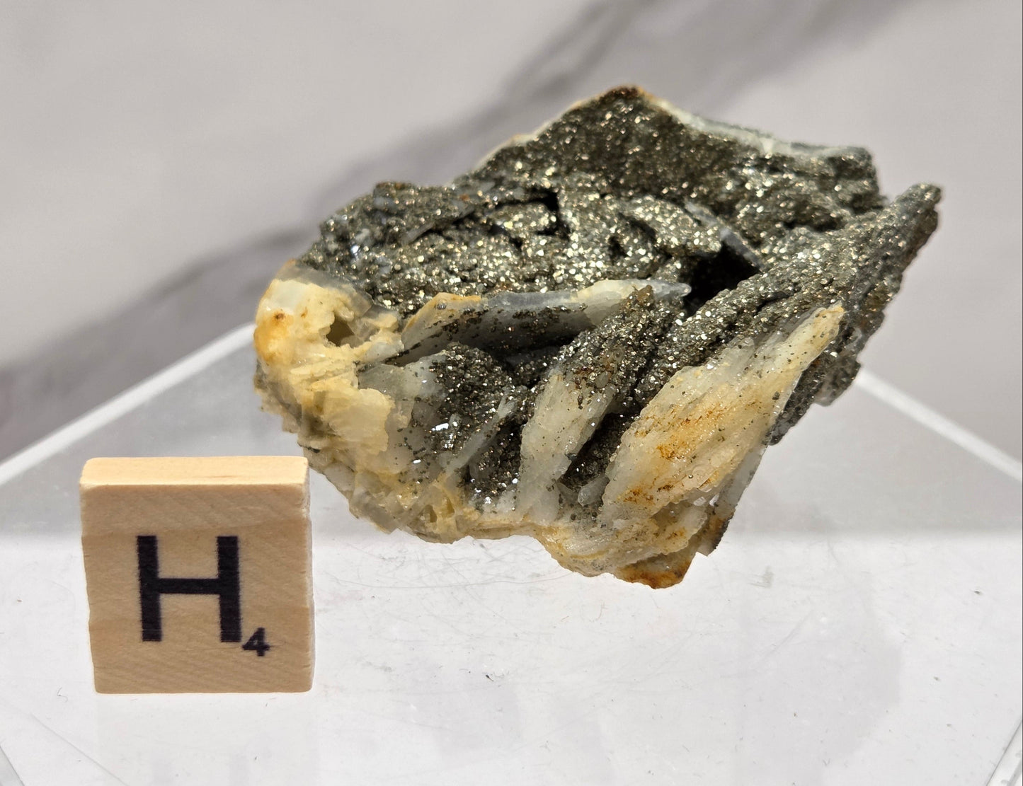 Mineral sample on a white background with a letter 'H' block