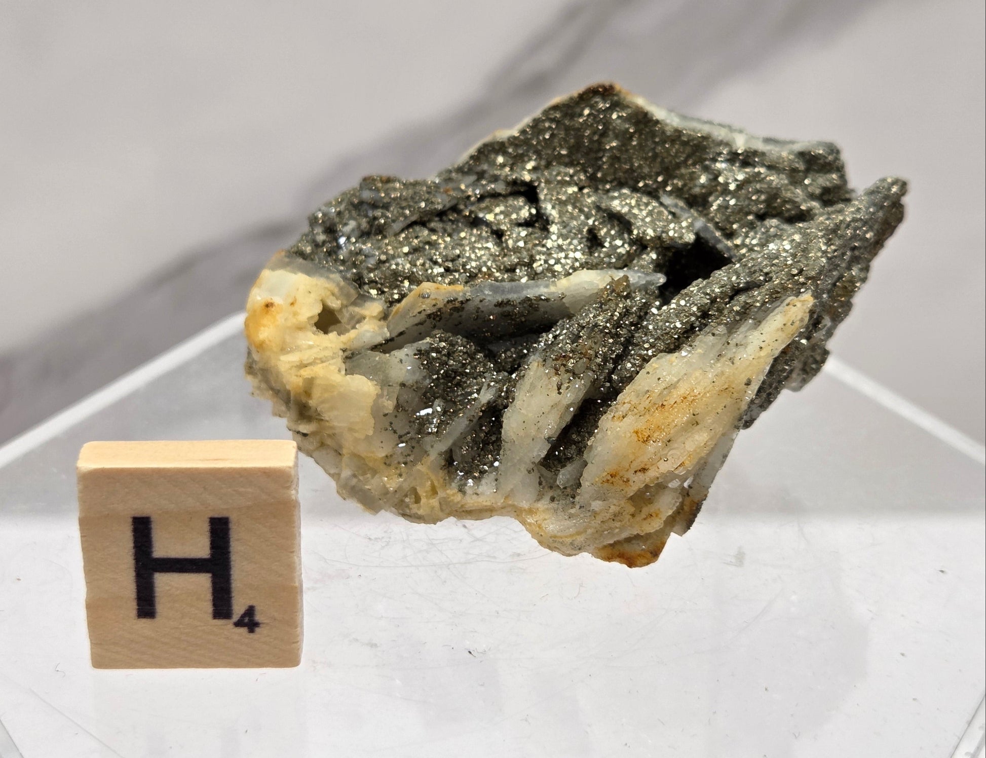 Mineral sample on a white background with a letter 'H' block