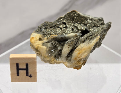 Mineral sample on a white background with a letter 'H' block