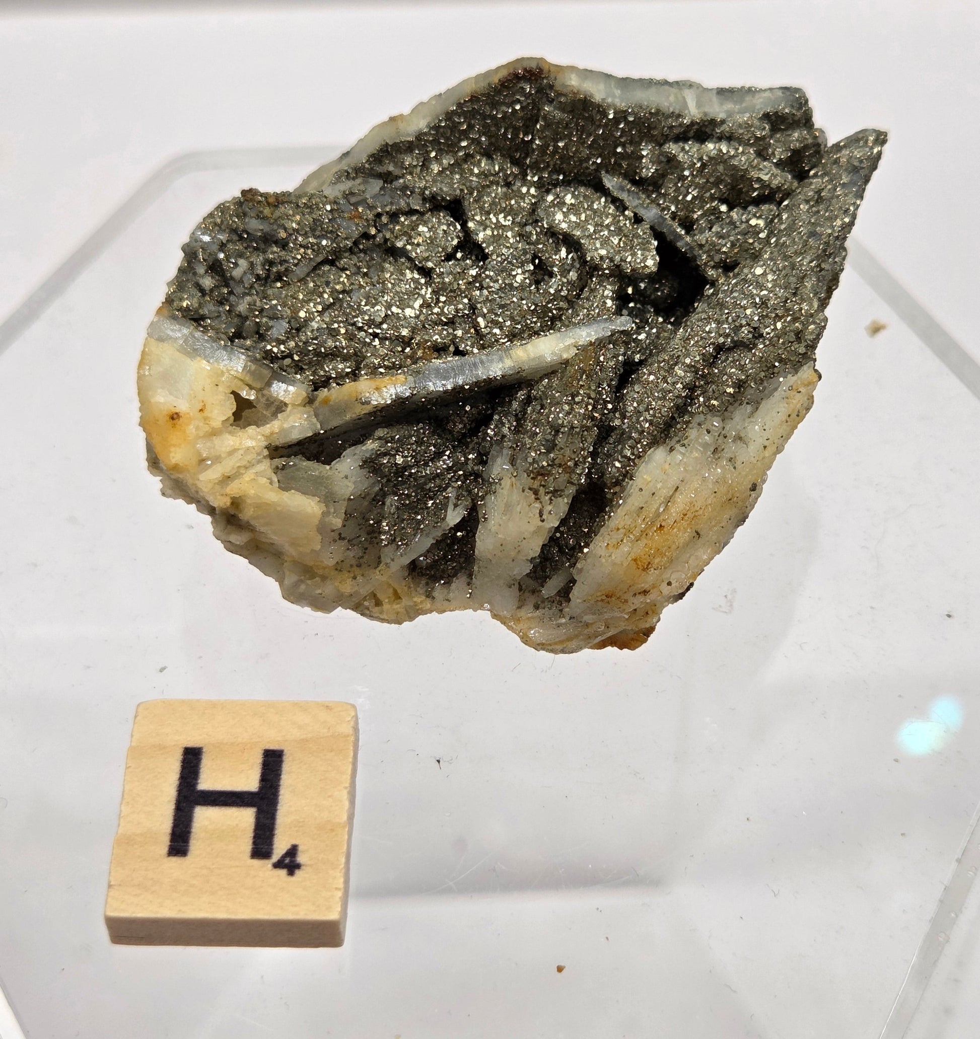 Mineral sample on a white background with a wooden block labeled 'H'.