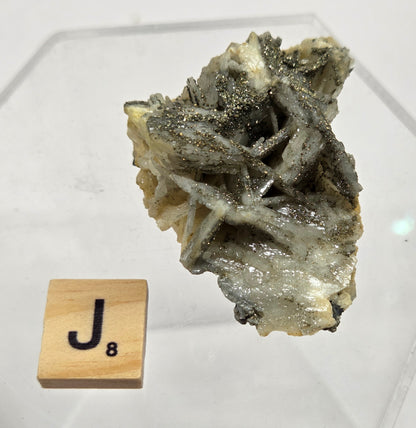 Mineral sample on a white background with a wooden letter 'J' block.