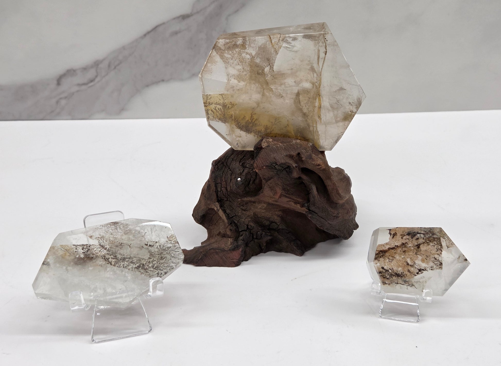 Dendritic quartz free forms, one on a wood stand, 2 on acrylic chairs, on a white background