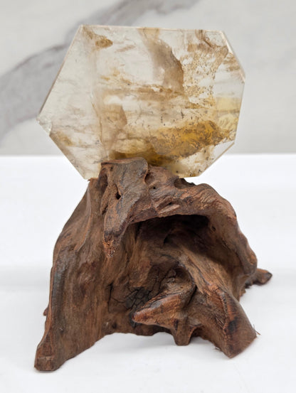 Dendritic Quartz free form on a wood stand against a white background