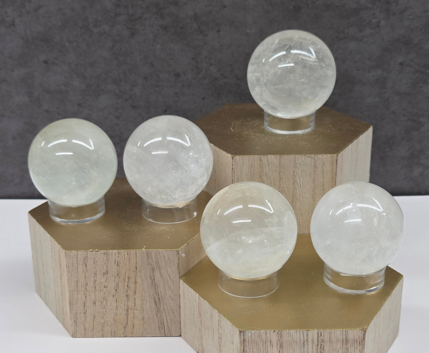Clear spheres on acrylic stands on a wood stand against a neutral background