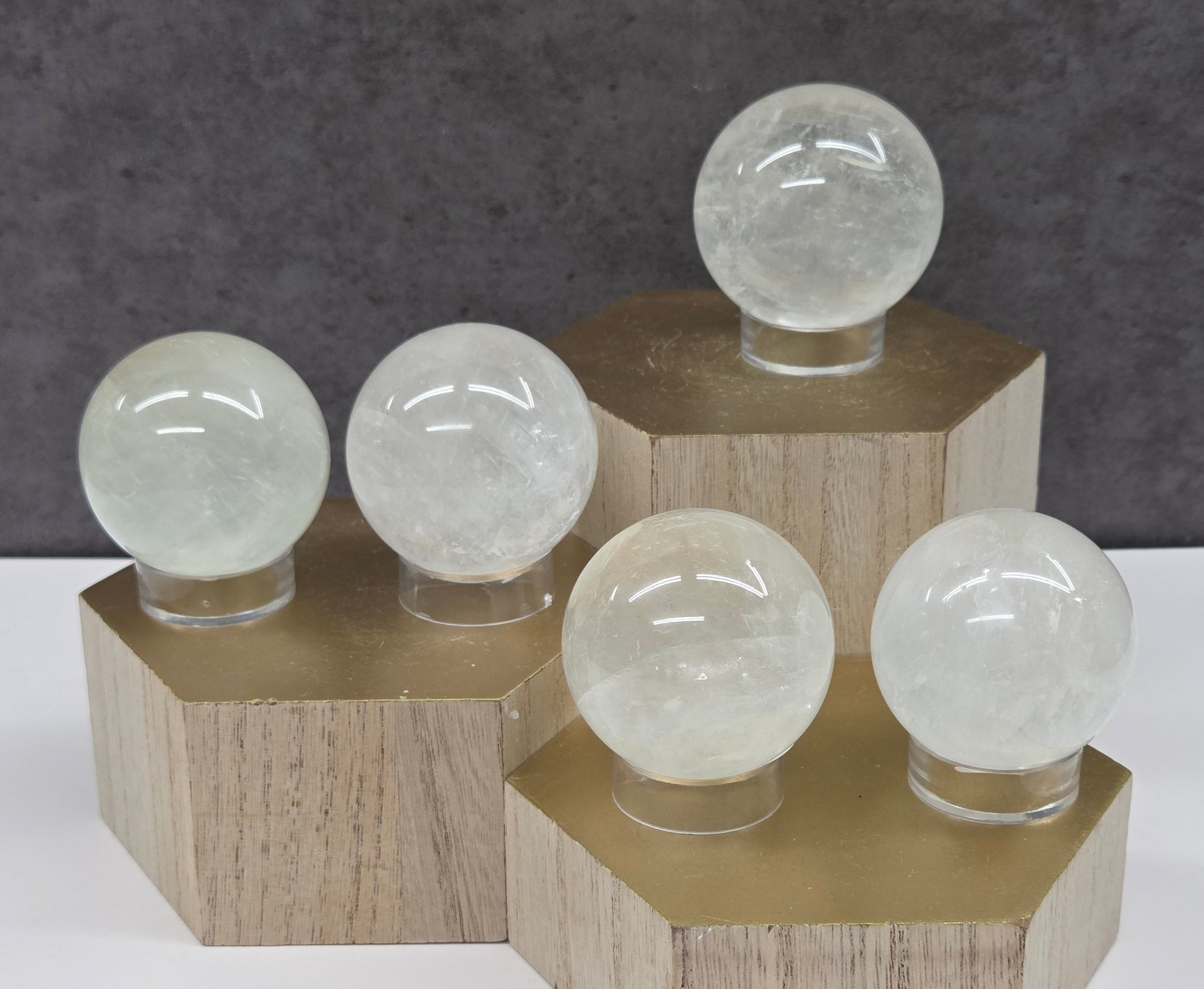 Clear spheres on acrylic stands on a wood stand against a neutral background