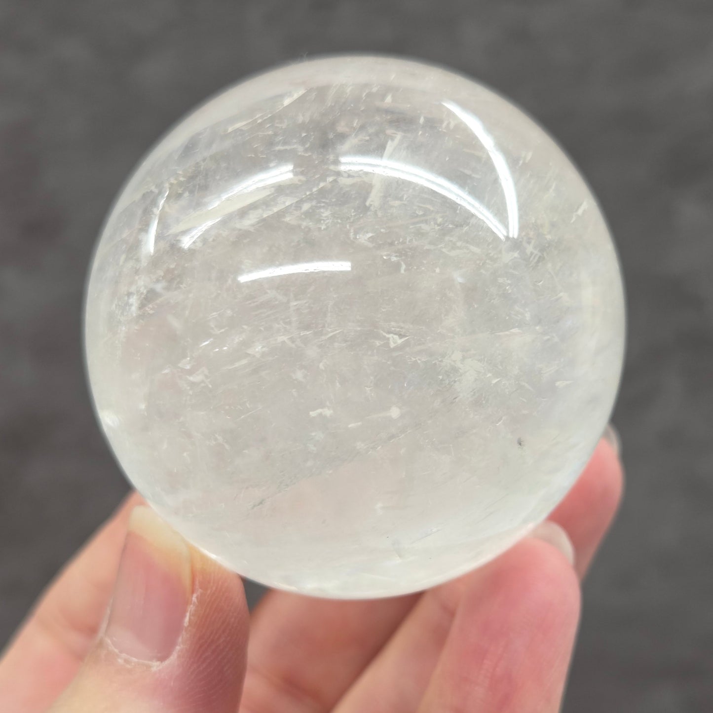 Clear crystal ball held by a hand against a dark background