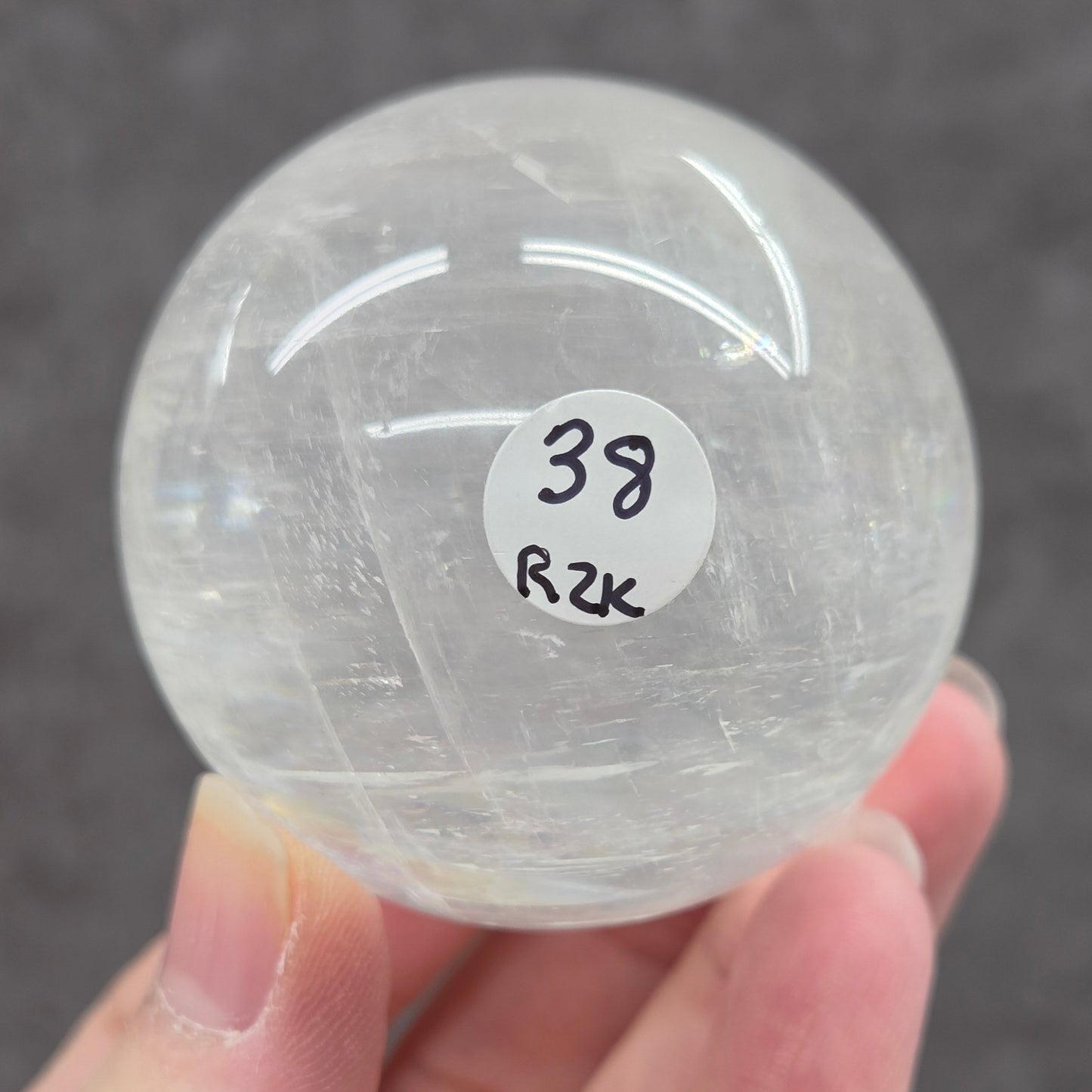 Clear crystal ball held by a hand with a blurred background