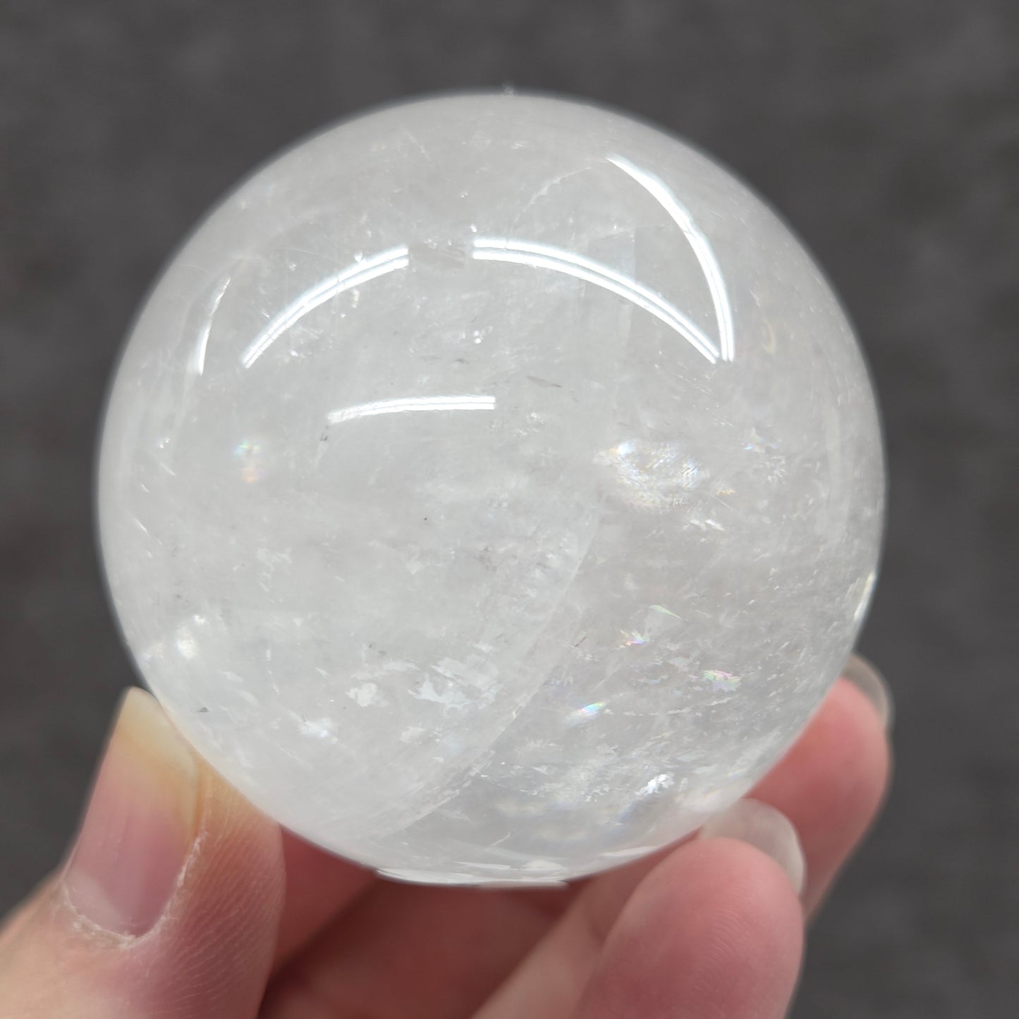 Clear crystal ball held in a hand against a dark background