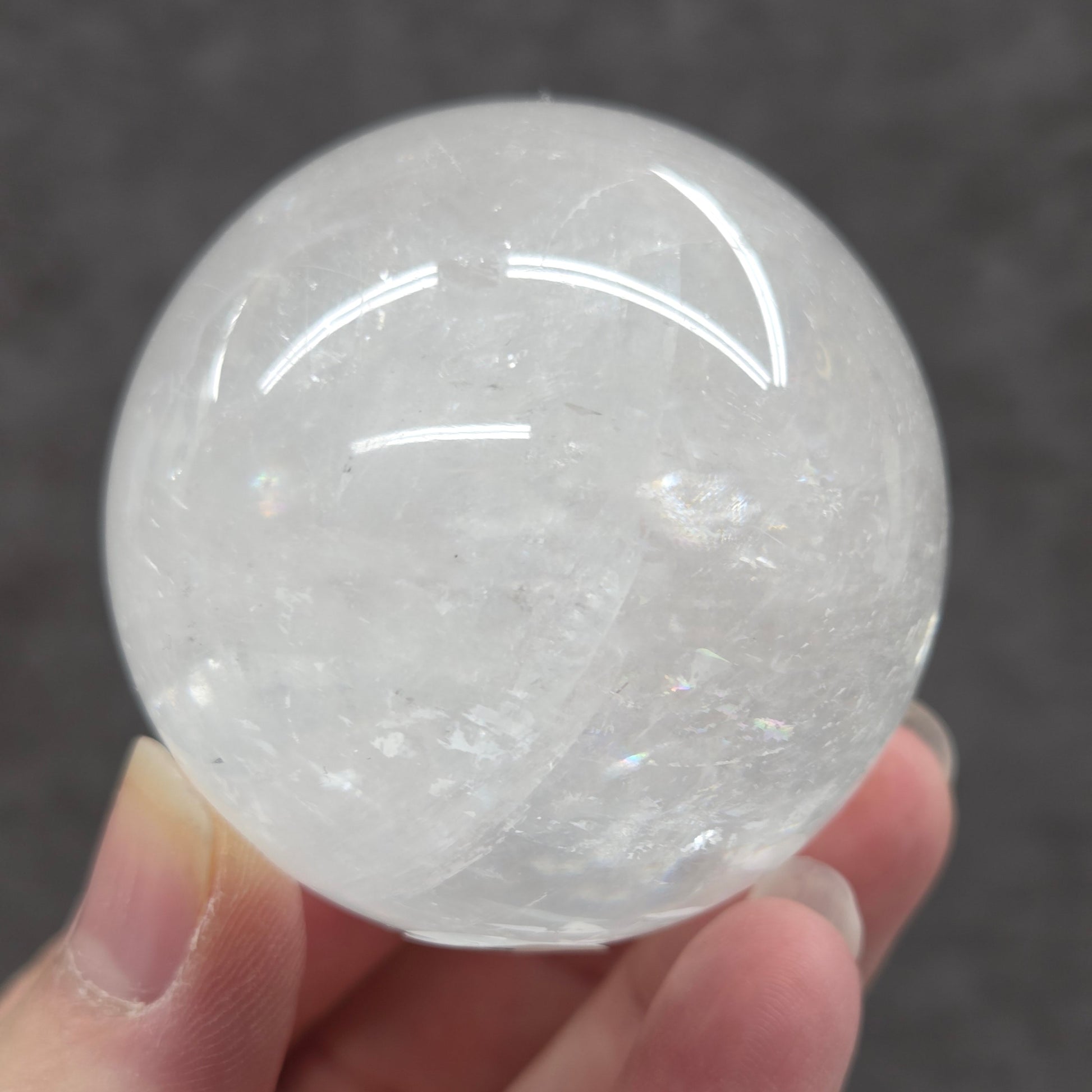 Clear crystal ball held in a hand against a dark background