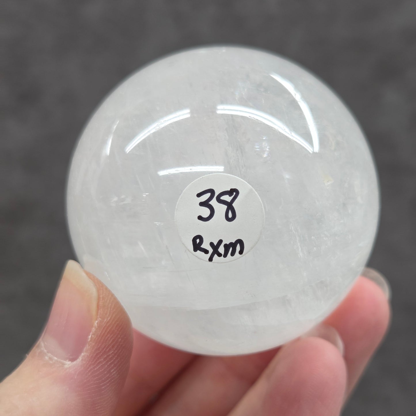 Clear crystal ball held by a hand with a label on a dark background