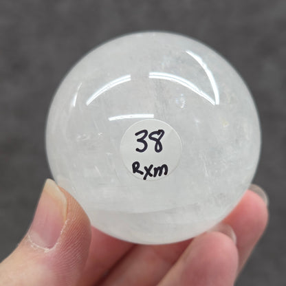 Clear crystal ball held by a hand with a label on a dark background