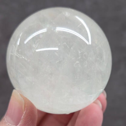 Hand holding a translucent crystal ball against a dark background