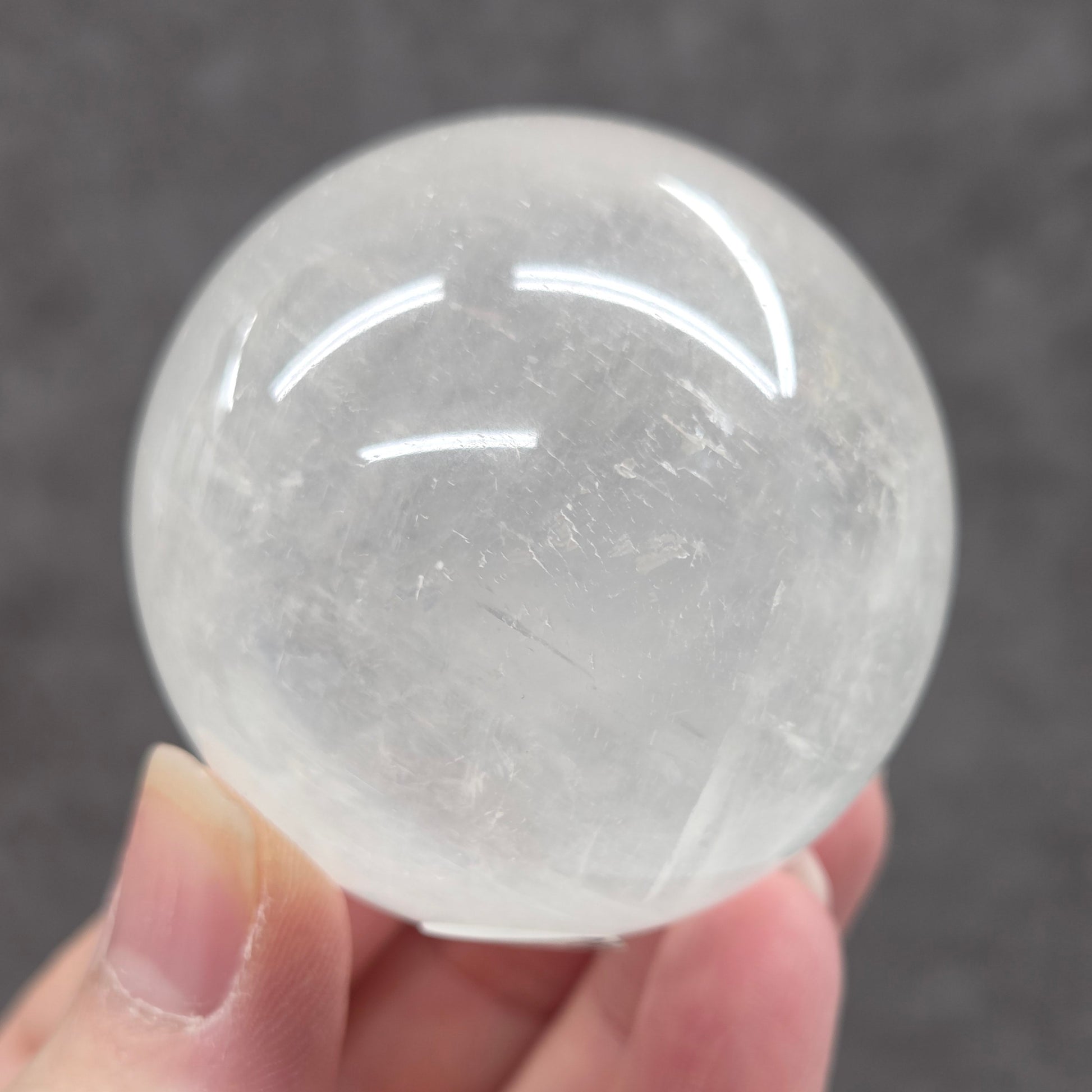 Clear crystal ball held by a hand against a dark background