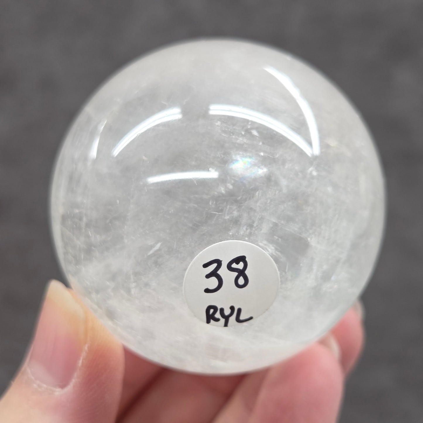 Clear crystal ball held by a hand with a label on a dark background