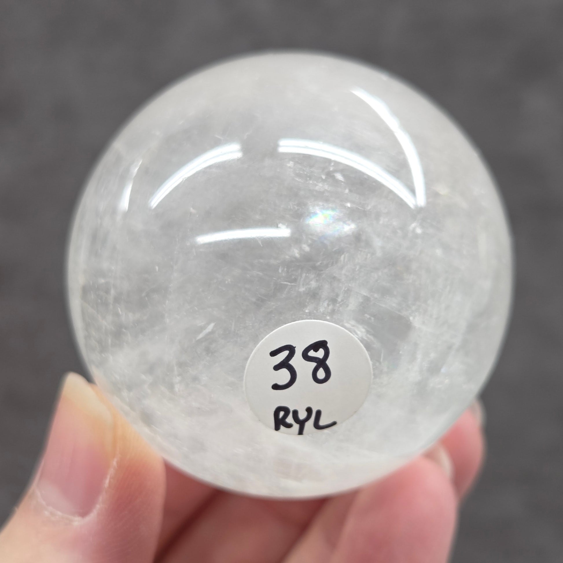 Clear crystal ball held by a hand with a label on a dark background