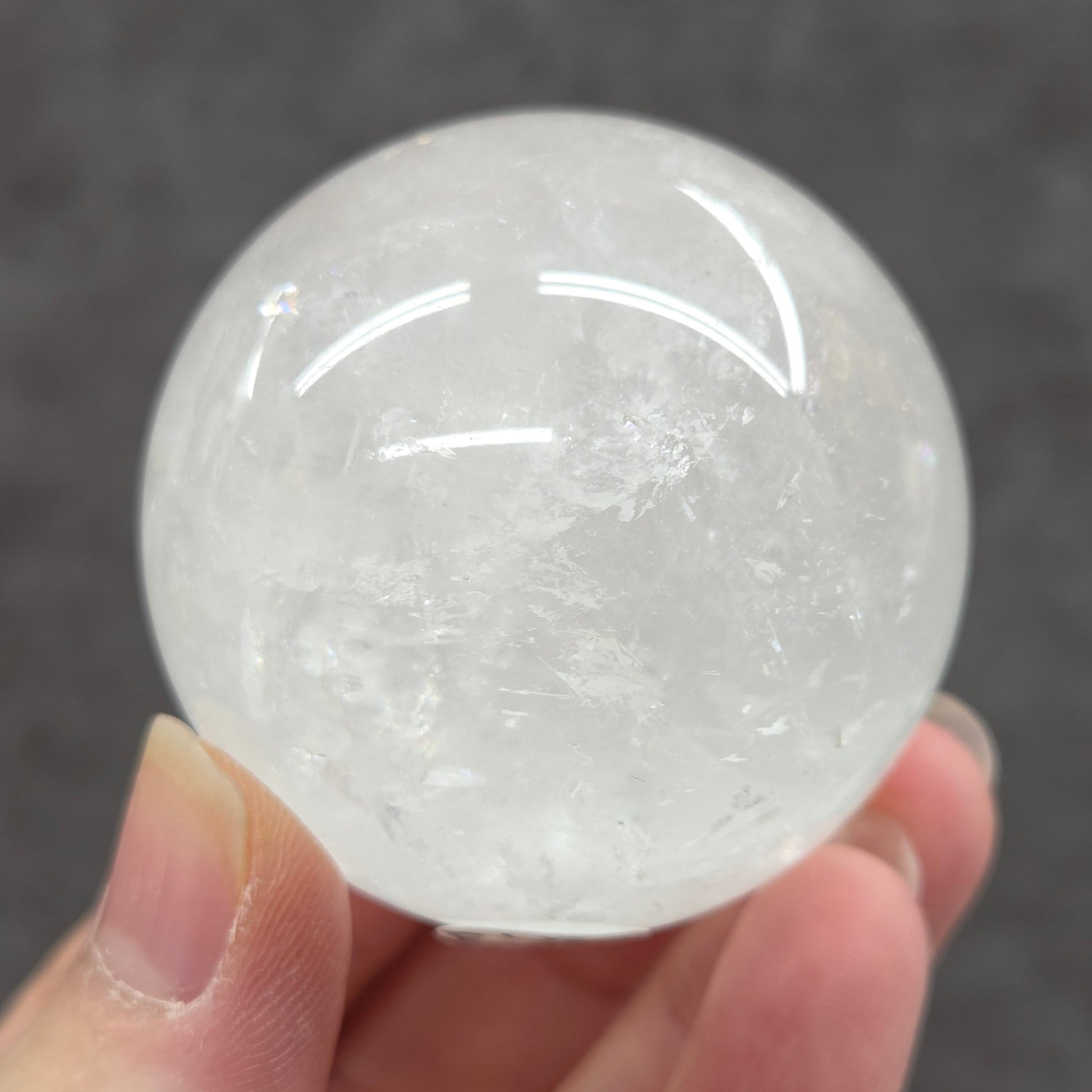 Hand holding a moon-shaped crystal against a dark background