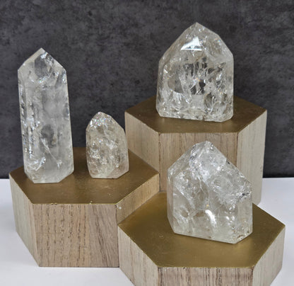 Clear Quartz crystal towers of varying sizes displayed against a neutral background.