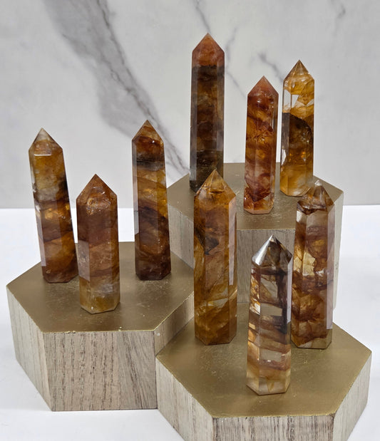 Golden Healer towers on a wood stand against a white background