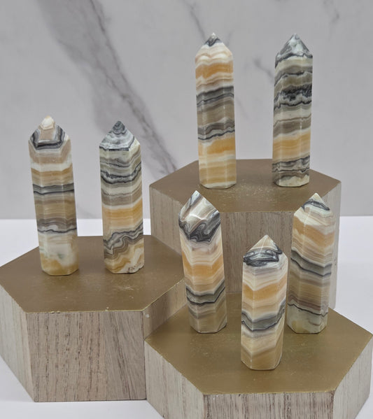 Banded Zebra Calcite towers on a wood base against a neutral background