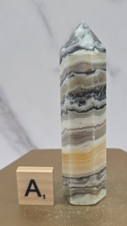 Banded Zebra Calcite tower on a wood base against a neutral background