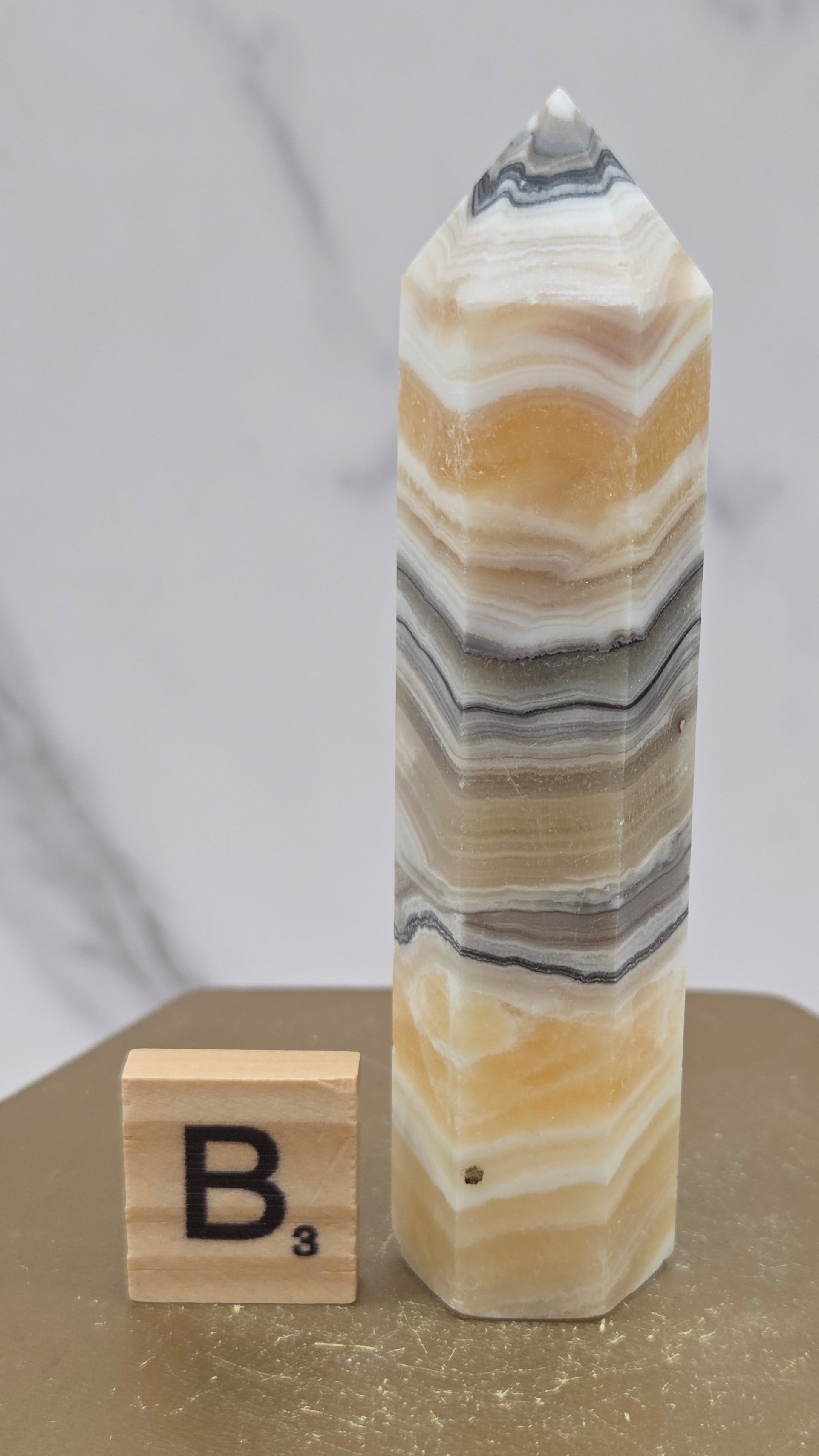 Banded Zebra Calcite tower on a wood base against a neutral background