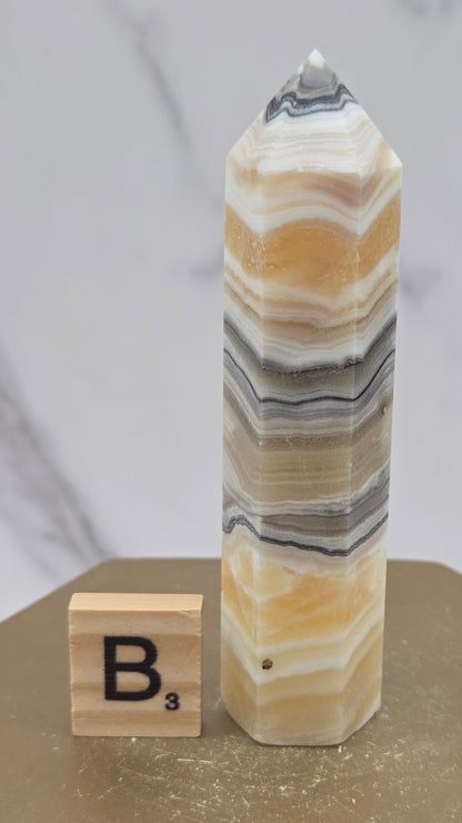 Banded Zebra Calcite tower on a wood base against a neutral background