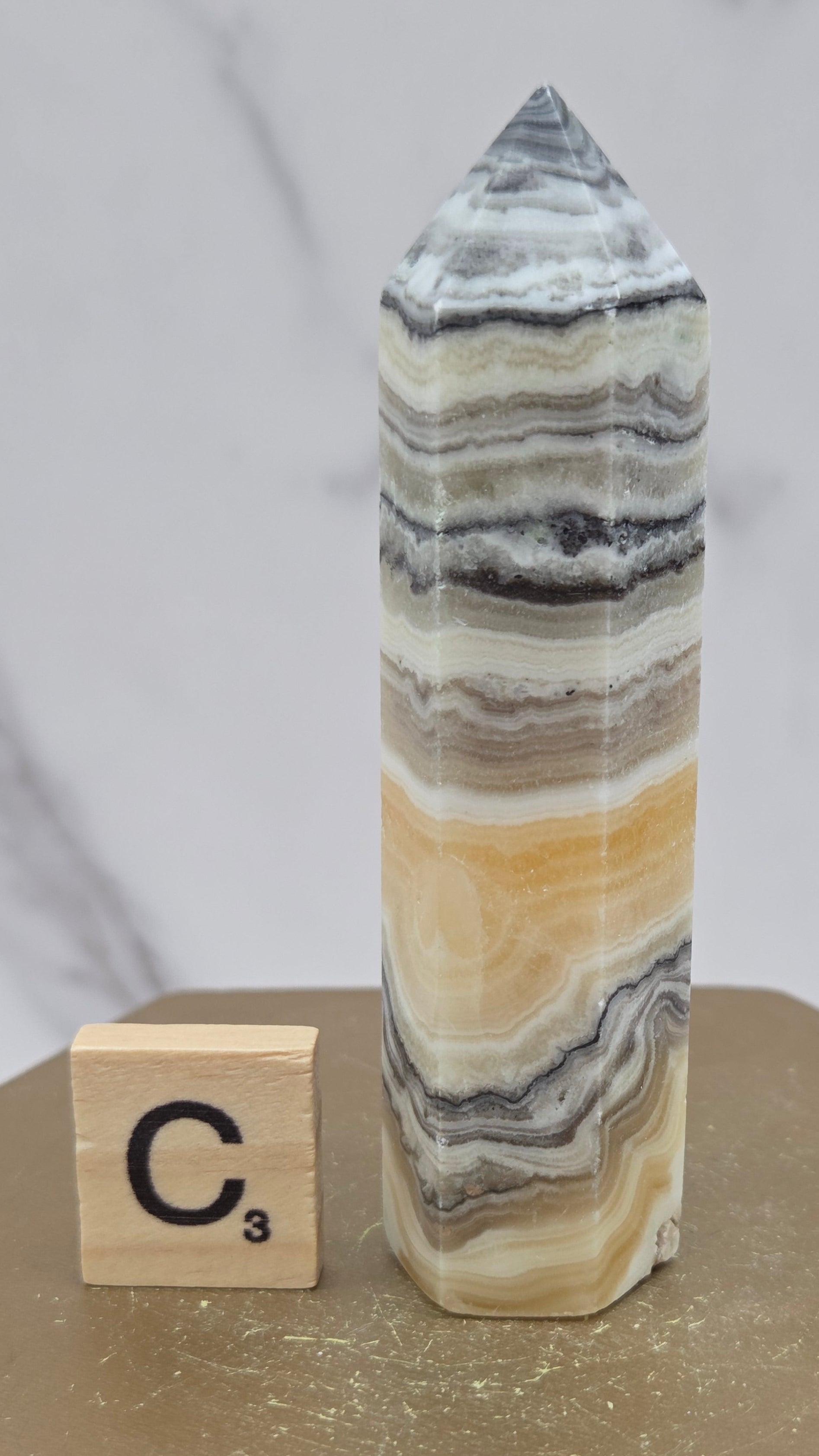 Banded Zebra Calcite tower on a wood base against a neutral background