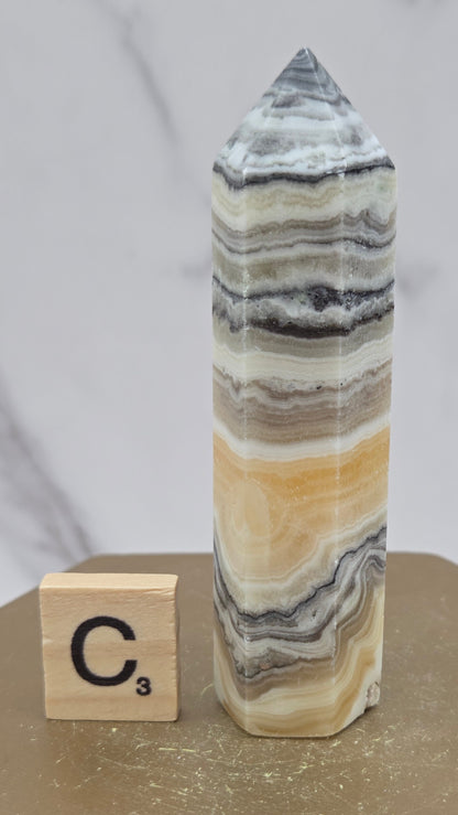 Banded Zebra Calcite tower on a wood base against a neutral background