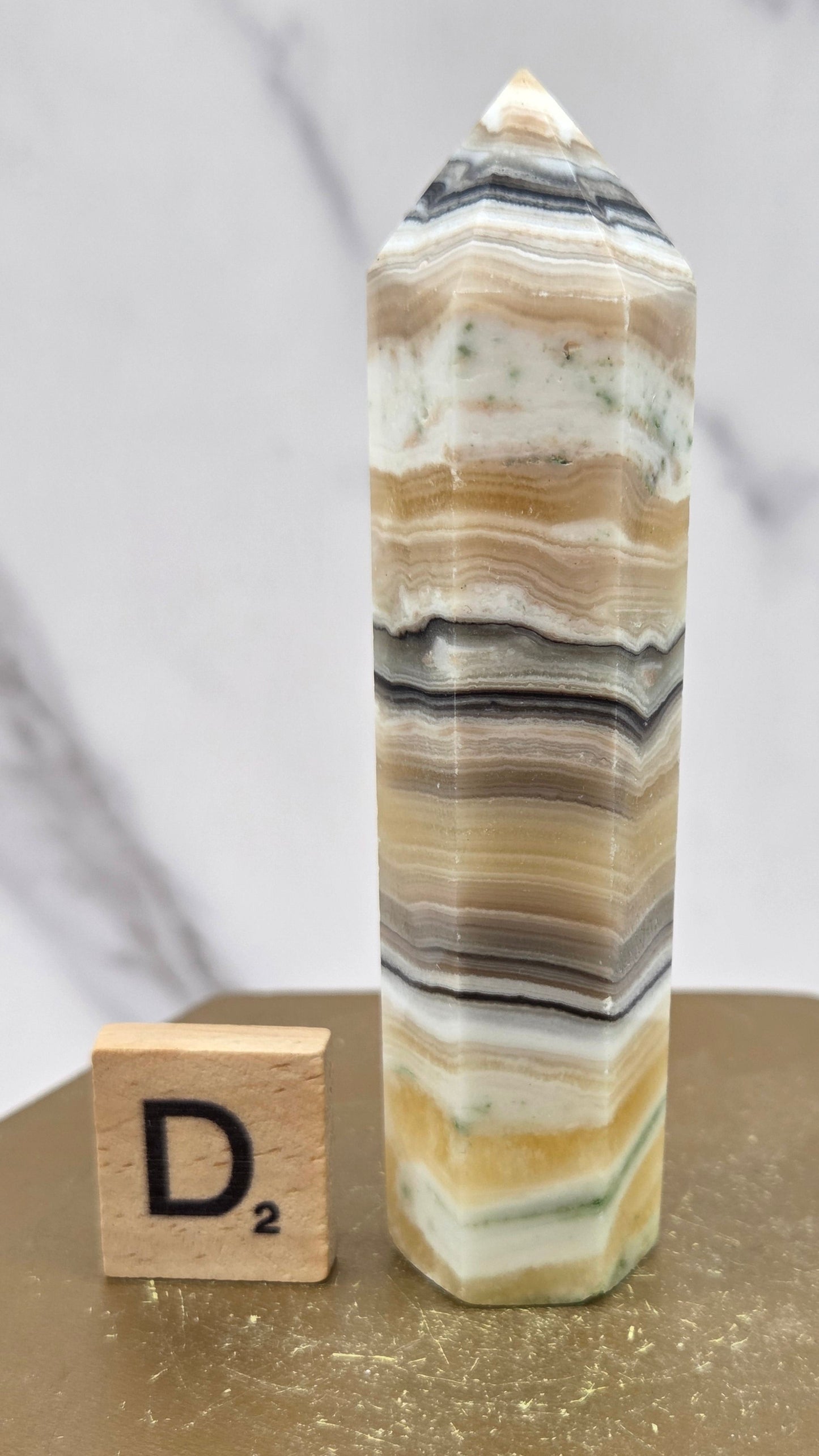 Banded Zebra Calcite tower on a wood base against a neutral background
