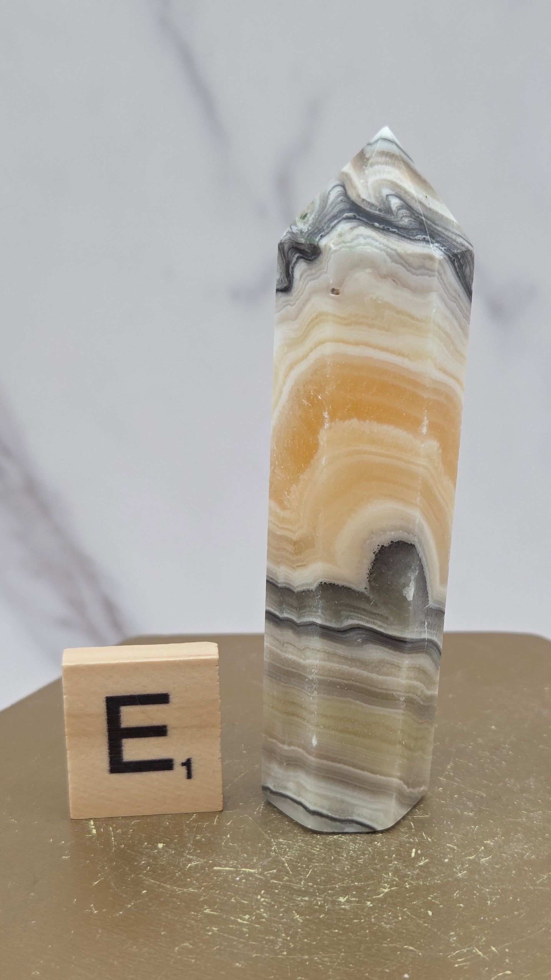 Banded Zebra Calcite tower on a wood base against a neutral background