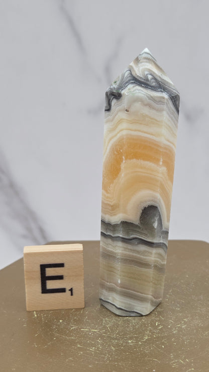 Banded Zebra Calcite tower on a wood base against a neutral background