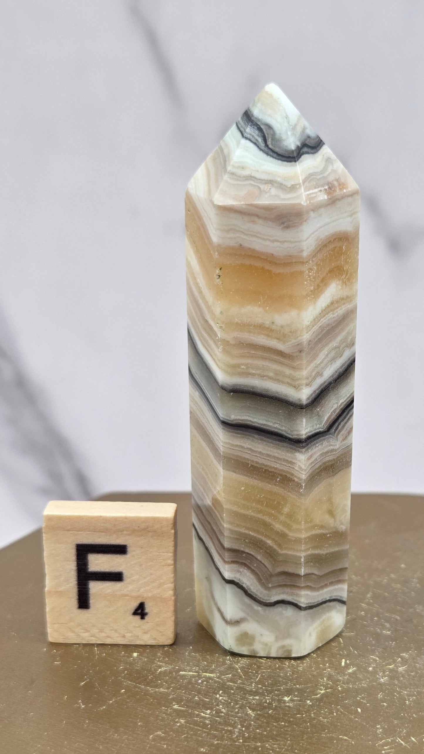 Banded Zebra Calcite tower on a wood base against a neutral background