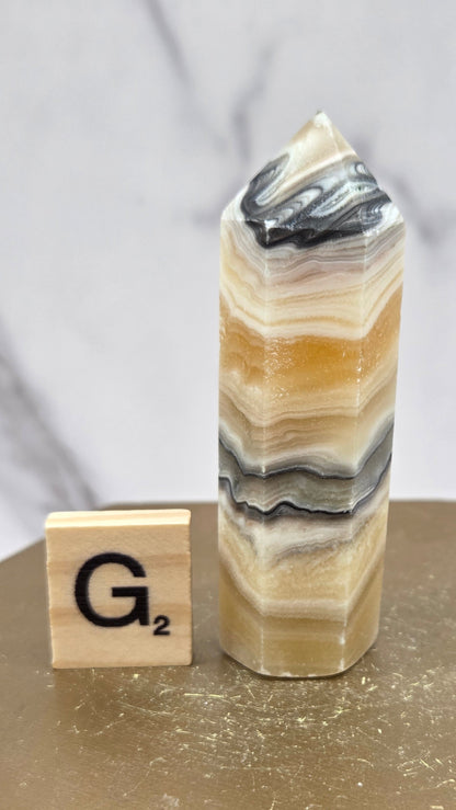 Banded Zebra Calcite tower on a wood base against a neutral background