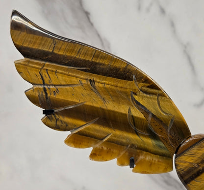 Decorative Tigers eye wings and a heart on a black stand on a neutral background