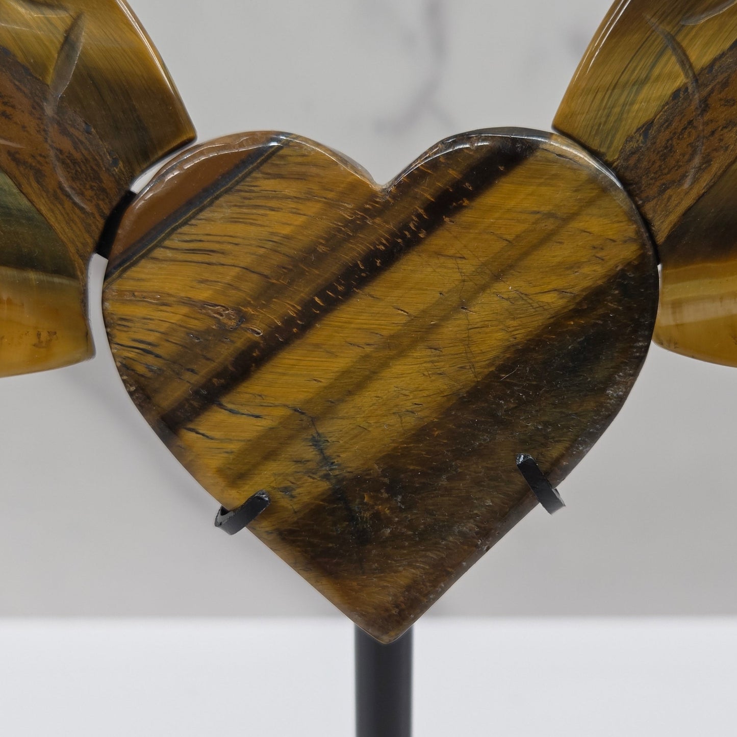 Decorative Tigers eye wings and a heart on a black stand on a neutral background