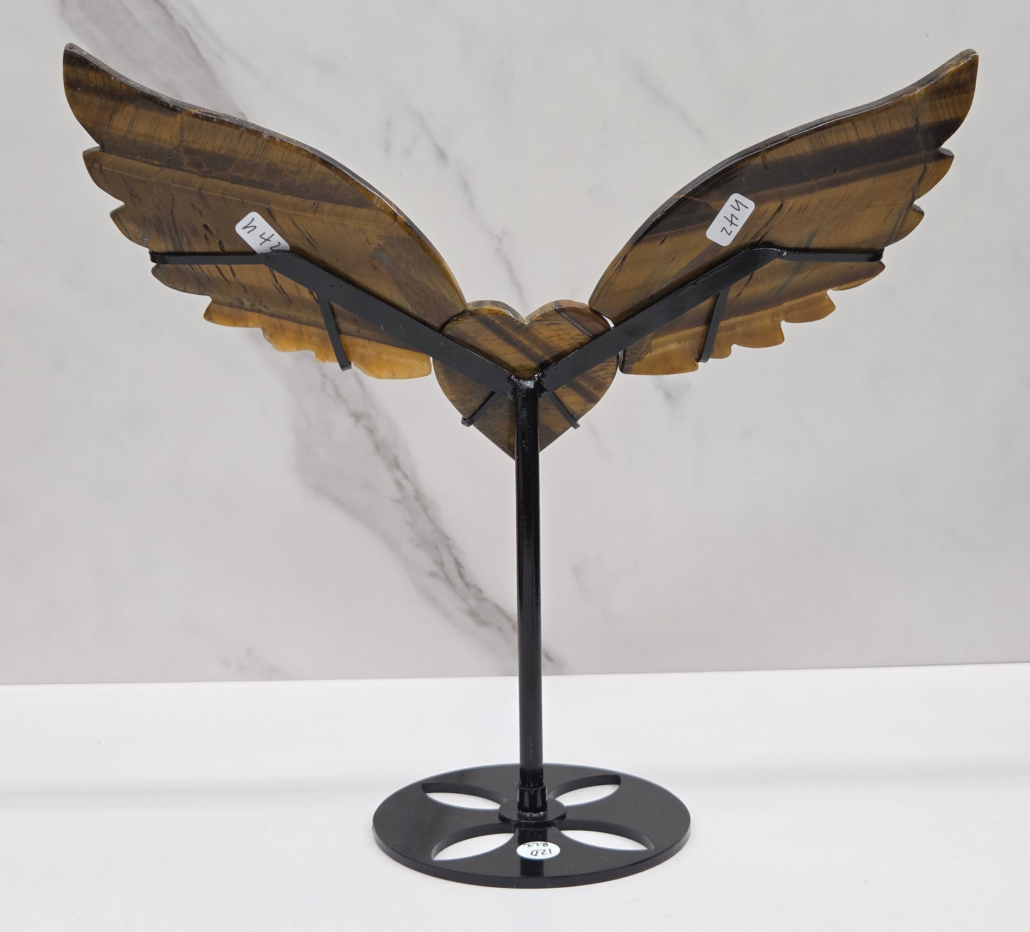 Decorative Tigers eye wings and a heart on a black stand on a neutral background