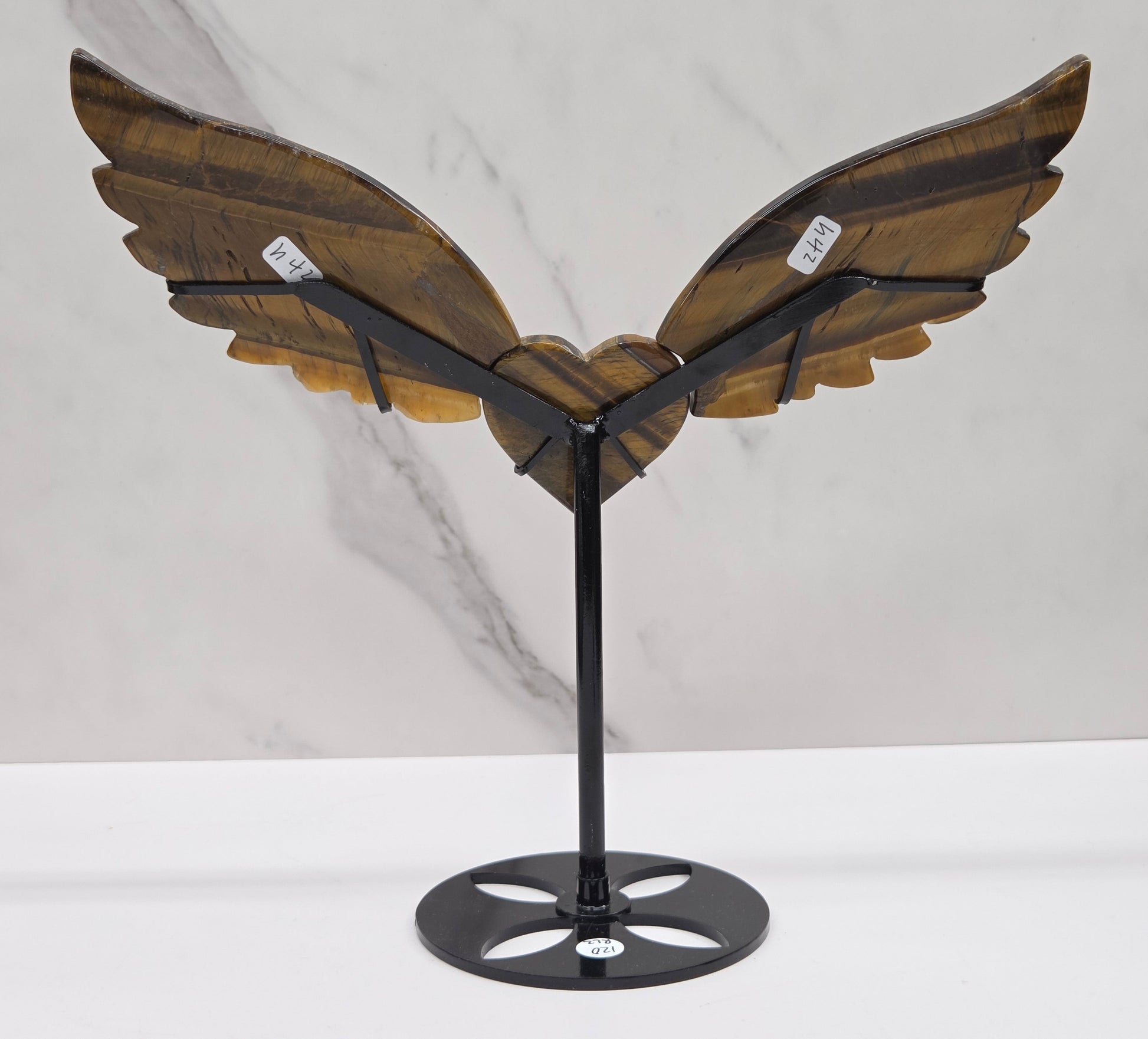 Decorative Tigers eye wings and a heart on a black stand on a neutral background