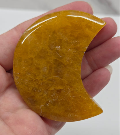 Hand holding a golden healer semi-circular stone against a white background