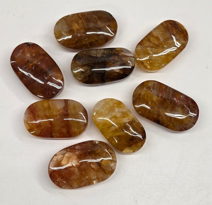 Set of polished golden healer stones on a white background