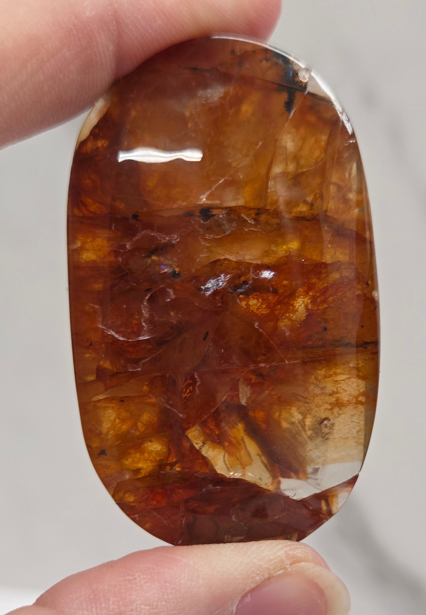 Hand holding a polished golden healer stone on a white background