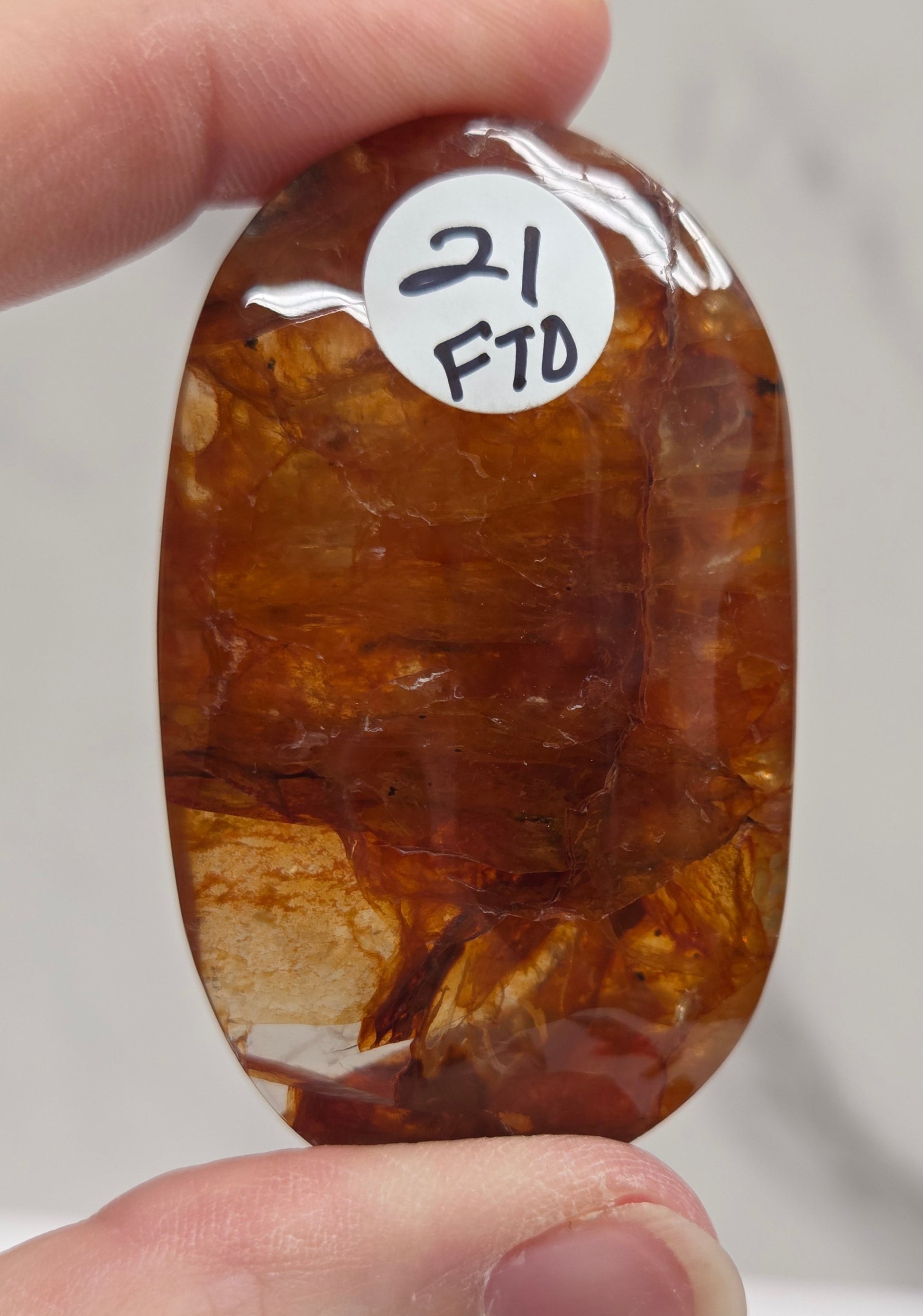 Hand holding a polished golden healer stone on a white background