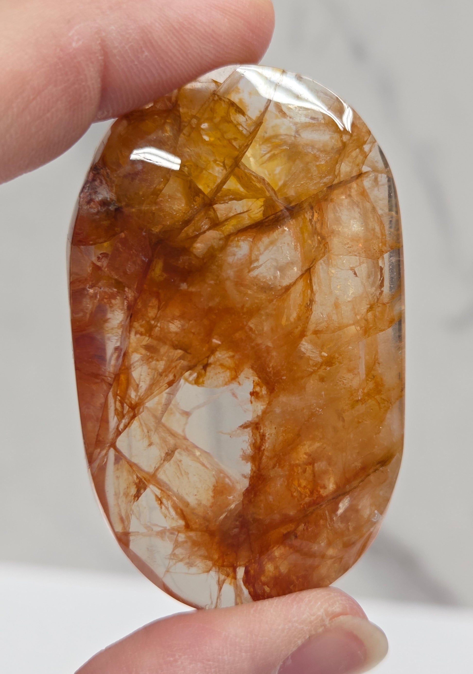 Hand holding a polished golden healer stone on a white background