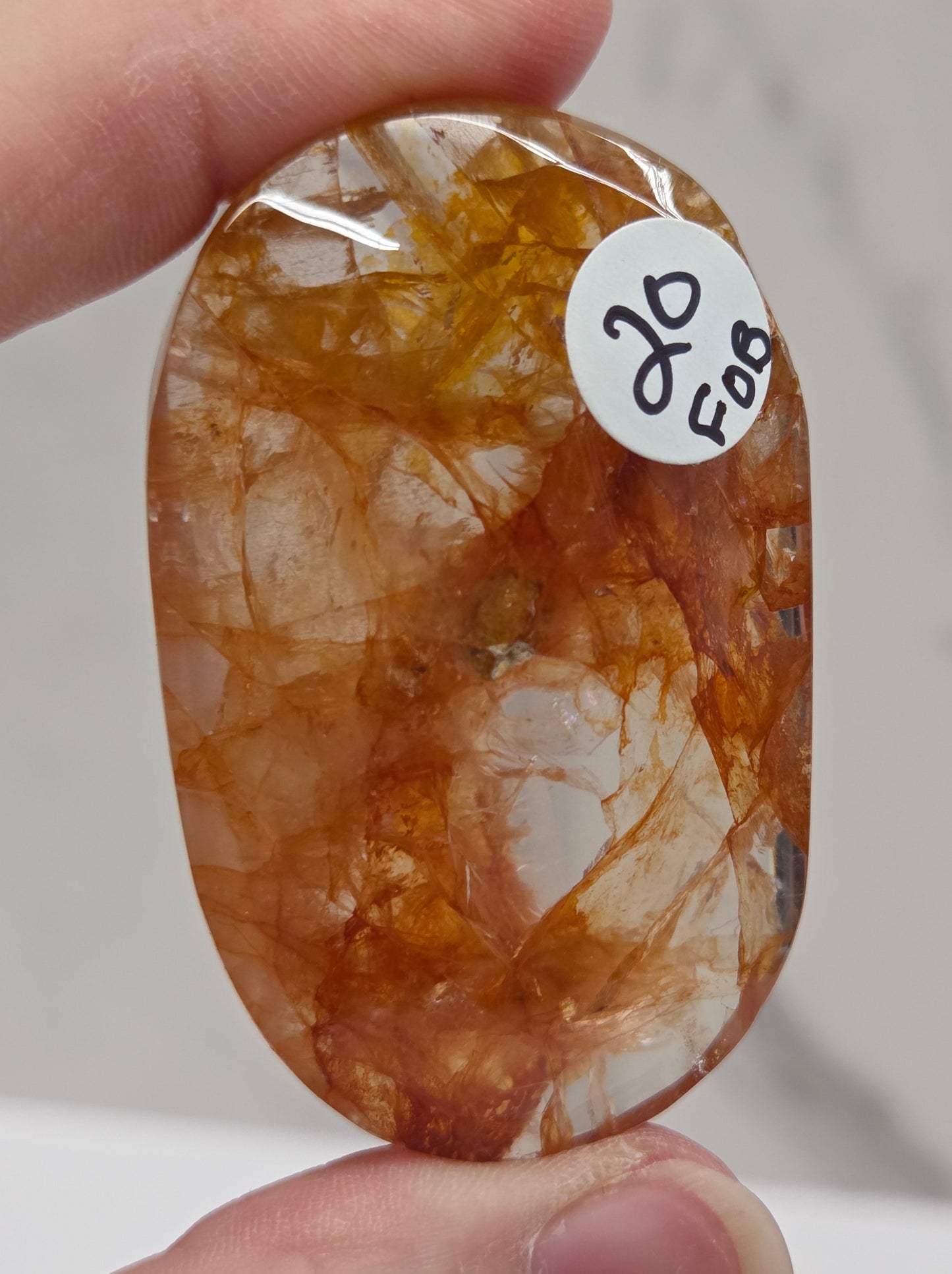 Hand holding a polished golden healer stone on a white background
