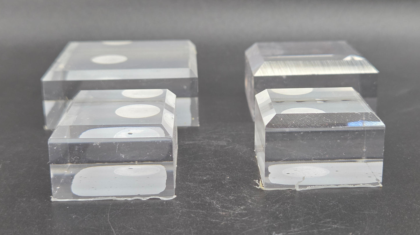 Four clear acrylic blocks on a dark surface