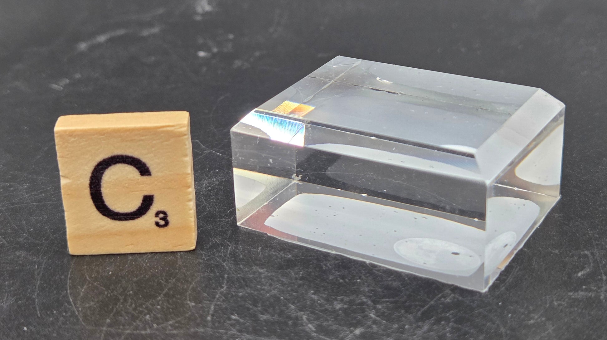 Clear rectangular block next to a wooden block with 'C' and number '3' on a dark surface