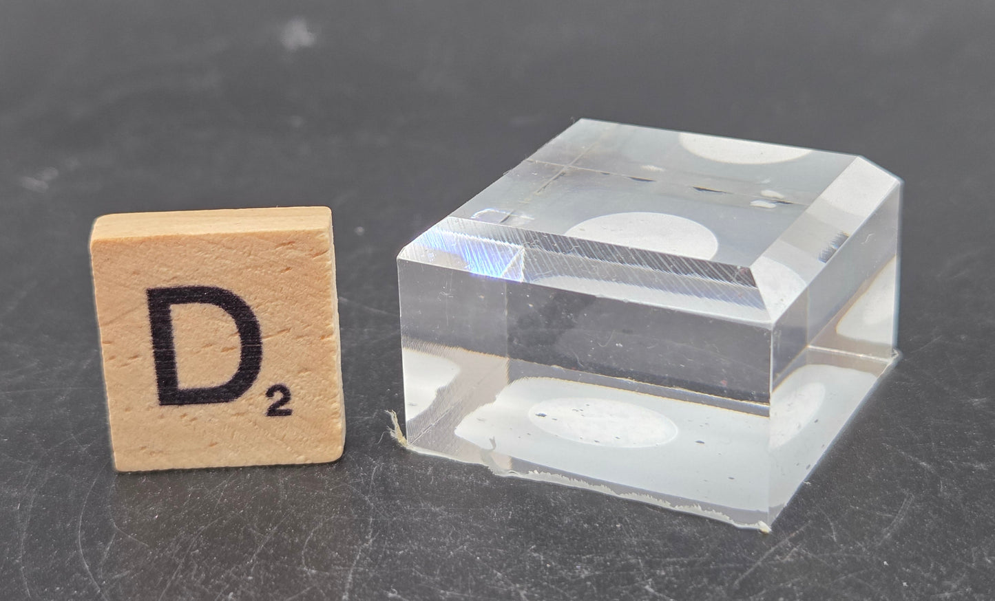Clear cube and wooden block with letter 'D' on a dark surface