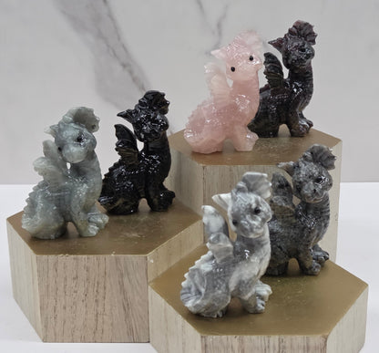 Dragon carvings in a variety of materials and colors on a wooden stand against a neutral background