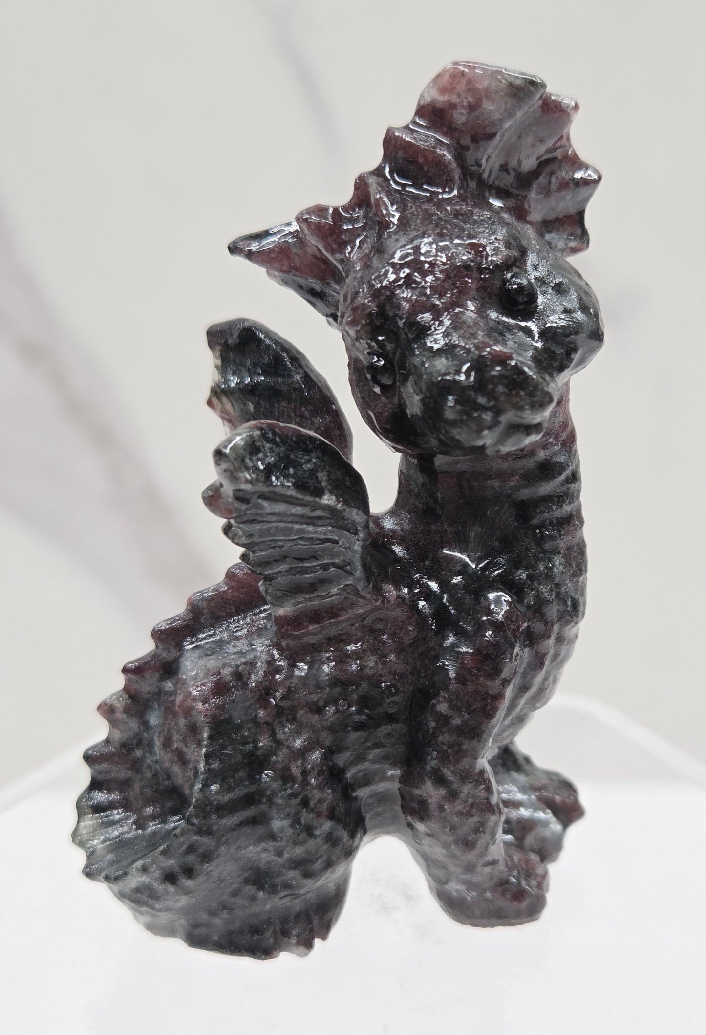 Garnet dragon carving on an acrylic stand against a neutral background