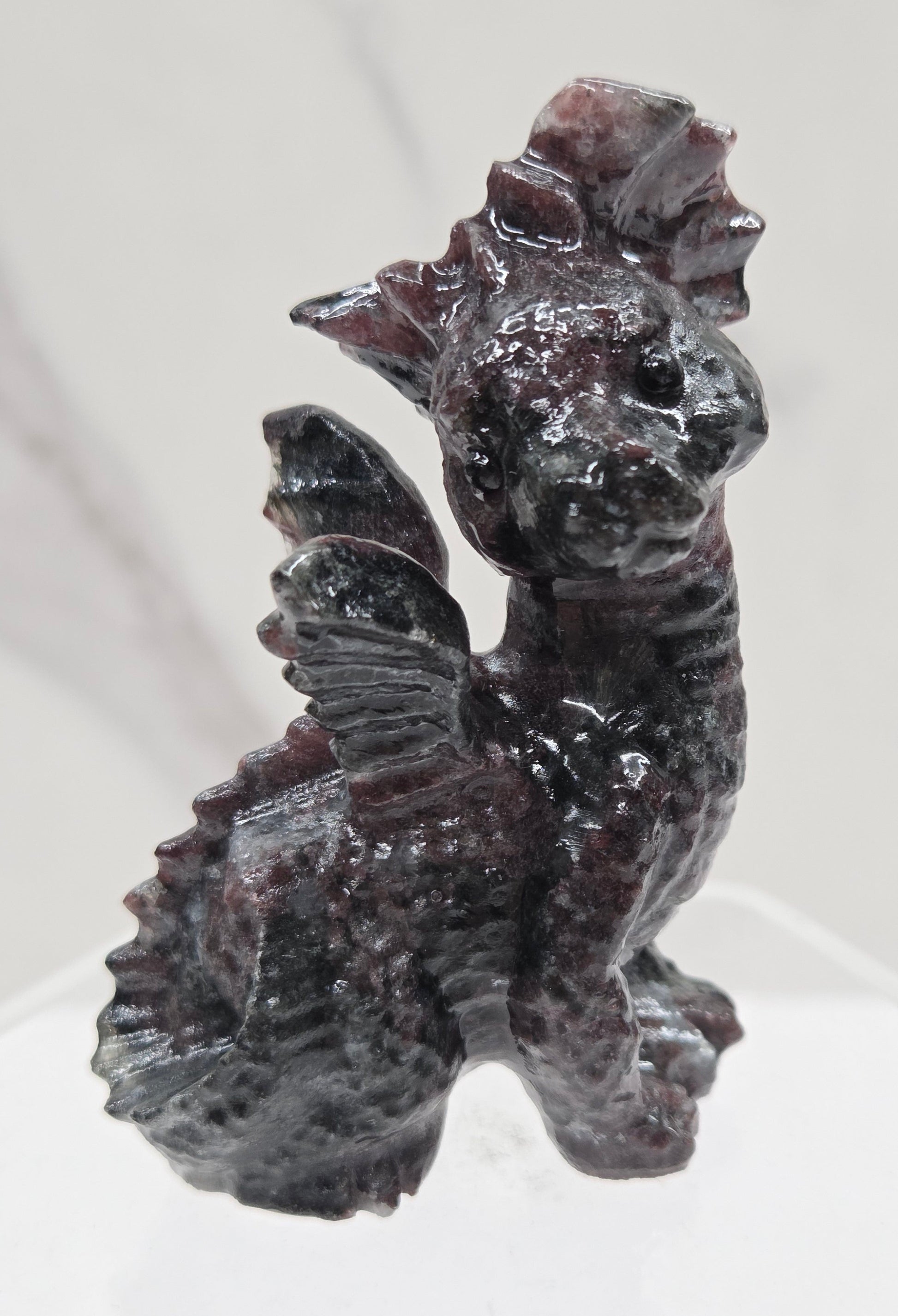 Garnet dragon carving on an acrylic stand against a neutral background